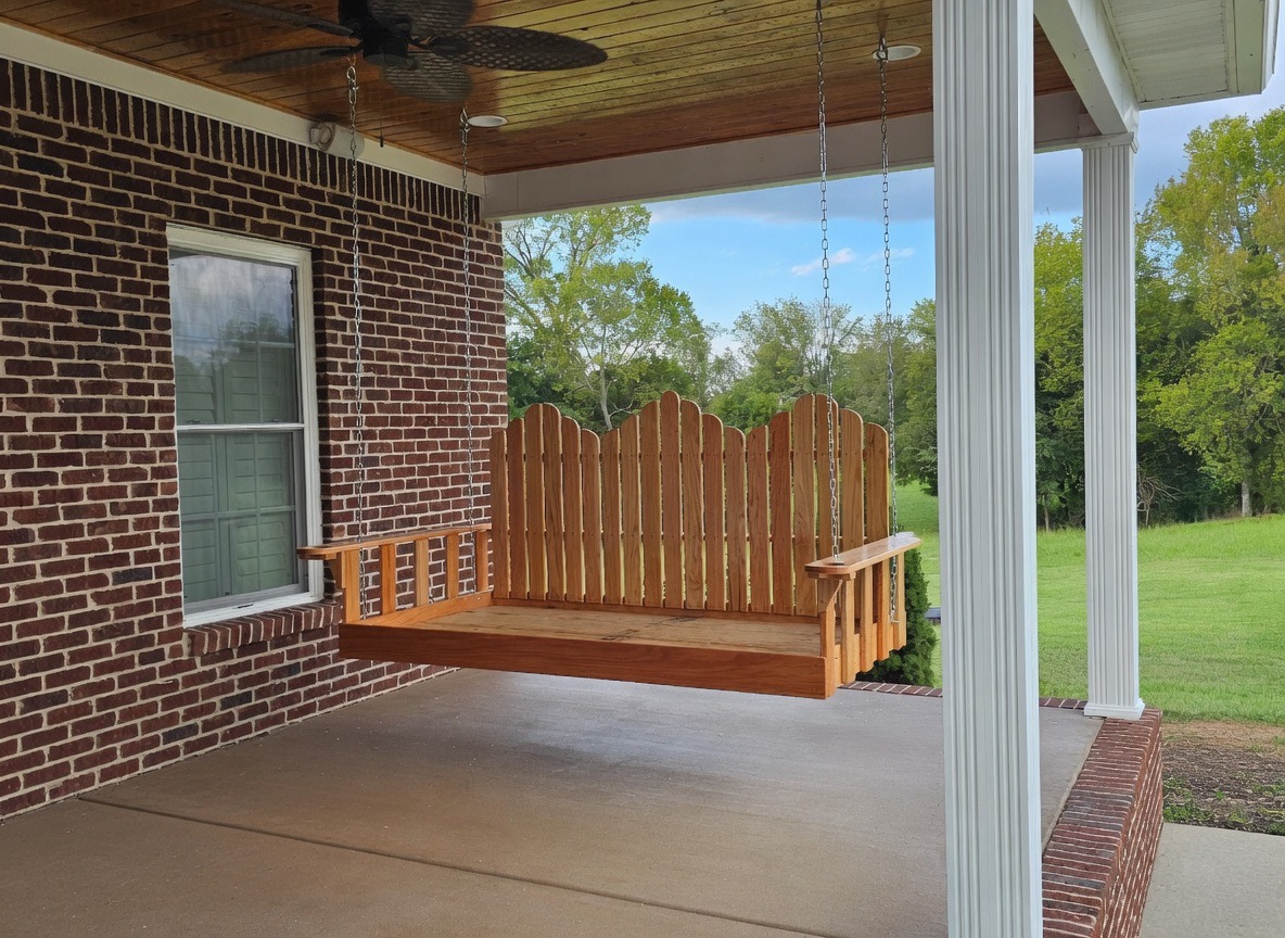 Custom handmade wooden porch swing on a covered brick porch